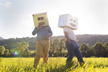 Boy playing while covering face with robot cardboard box - VABF03520