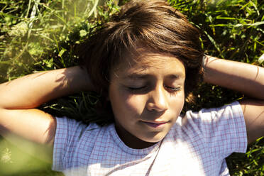 Junge mit Händen hinter dem Kopf schlafend im Gras auf einer Wiese - VABF03528