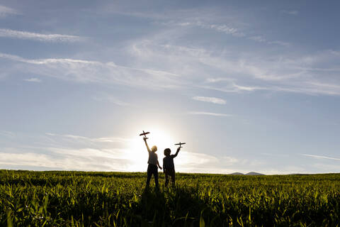 Silhouette of boys holding toy while standing against clear sky stock photo