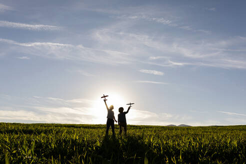 Silhouette eines Jungen, der ein Spielzeug hält, während er vor einem klaren Himmel steht - VABF03545