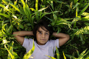 Lächelnder Junge, der im Gras auf einer Wiese liegt - VABF03547