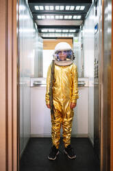 Boy wearing space suit standing in open elevator - JCMF01474