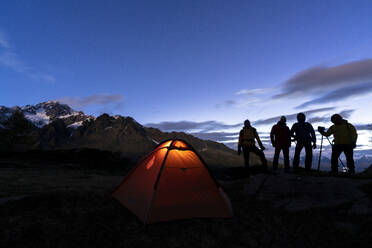 Hikers camping with tent photographing Monte Disgrazia at night, Valmalenco, Sondrio province, Valtellina, Lombardy, Italy, Europe - RHPLF17545