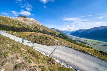 Blick auf Touristen, die mit dem Trottinett auf dem Bergweg fahren, Celerina, Engadin, Kanton Graubünden, Schweiz, Europa - RHPLF17556