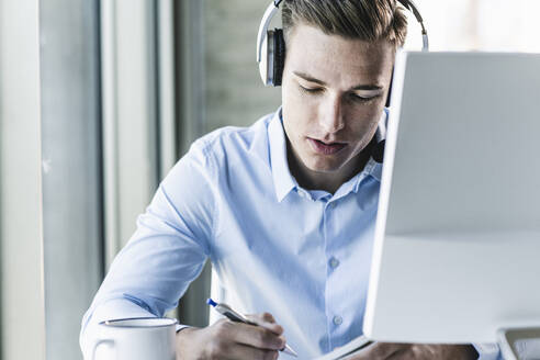 Nahaufnahme eines männlichen Kundenvertreters, der ein Headset trägt, während er in einem Callcenter arbeitet - UUF21479