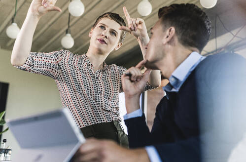 Businessman looking at female professional explaining to him in office - UUF21513