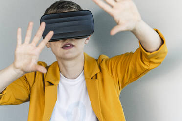 Close-up of businesswoman looking through virtual reality simulator against wall in office - UUF21560