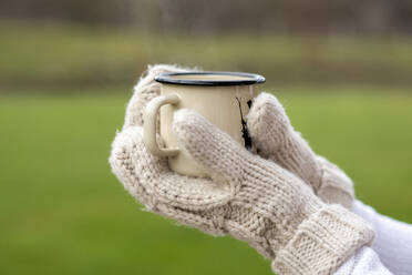 Hände einer jungen Frau mit Handschuhen halten einen Kaffeebecher im Freien - LBF03230