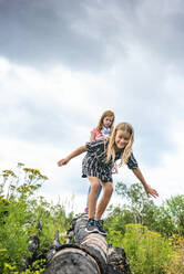 Two Young Girls Walking on Log - CAVF89306