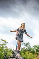 Two Young Girls Walking on a Log - CAVF89307