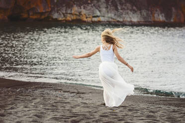 Junges blondes Mädchen tanzt am Strand - CAVF89309