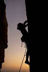 Schöne Aussicht auf die Silhouette eines kletternden Mannes bei Sonnenuntergang - CAVF89388