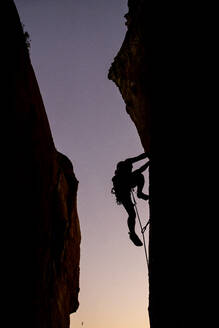 Schöne Aussicht auf die Silhouette eines kletternden Mannes bei Sonnenuntergang - CAVF89389