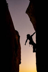 Beautiful view to silhouette of man climbing during sunset - CAVF89390