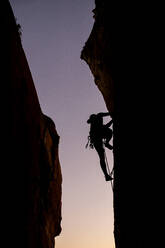 Beautiful view to silhouette of man climbing during sunset - CAVF89391