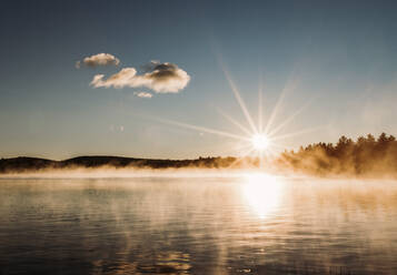 Aufgehende Sonne Stern über friedlichen dunstigen und nebligen See in Maine Wälder - CAVF89398