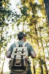 Male hiker with backpack standing in forest - GRCF00364