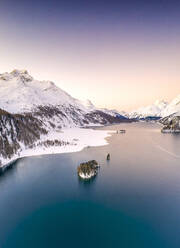 Aerial by drone of Lake Sils surrounded by snowy peaks during a winter sunrise, Engadine, canton of Graubunden, Switzerland, Europe - RHPLF17638