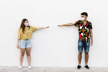 Young friends keeping social distancing while standing against wall - XLGF00587