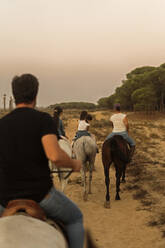 Familie reitet Pferde auf Landschaft gegen klaren Himmel bei Sonnenuntergang - ERRF04445