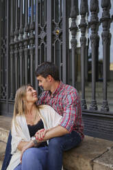 Couple sitting on steps against fence - SASF00106