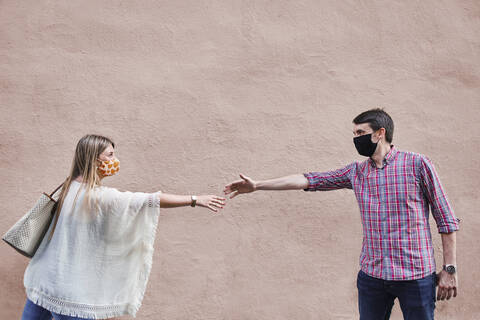 Paar hält sozialen Abstand, während es an der Wand steht, lizenzfreies Stockfoto