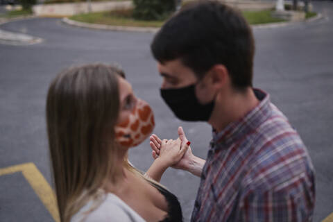 Couple wearing protective face mask with hand in hand standing on street stock photo