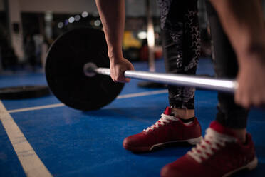 Abgeschnittene weibliche Athletin, die eine Langhantel im Fitnessstudio stemmt - CAVF89413