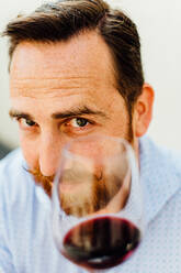Nahaufnahme eines Mannes mit Schnurrbart, der ein Glas Rotwein hält - CAVF89465