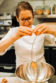Weiblicher Koch beim Eierschlagen in einer Restaurantküche, Lifestyle-Clo - CAVF89486