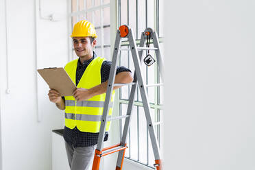 Architect wearing sunglasses and hardhat smiling while standing at  construction site stock photo