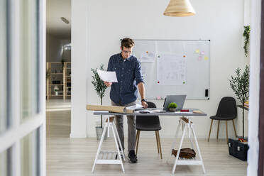 Junger Mann steht bei der Arbeit im Büro - GIOF08869