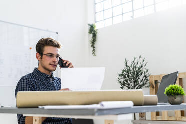 Architekt, der einen Plan bespricht, während er am Schreibtisch im Büro sitzt - GIOF08887