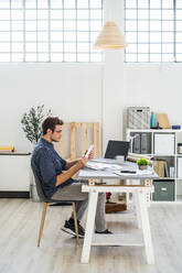 Architekt, der im Büro sitzend an einem digitalen Tablet arbeitet - GIOF08889
