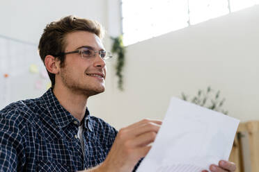 Junger Mann lächelt bei der Arbeit im Büro - GIOF08893