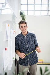 Smiling man standing while leaning on whiteboard at office - GIOF08909