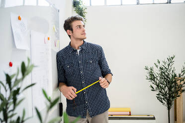 Thoughtful man leaning on whiteboard while standing at office - GIOF08910