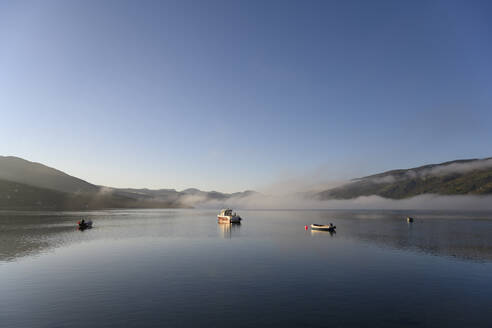 UK, Scotland, Ullapool, Clear sky over boats floating in Loch Broom during foggy weather - ELF02188