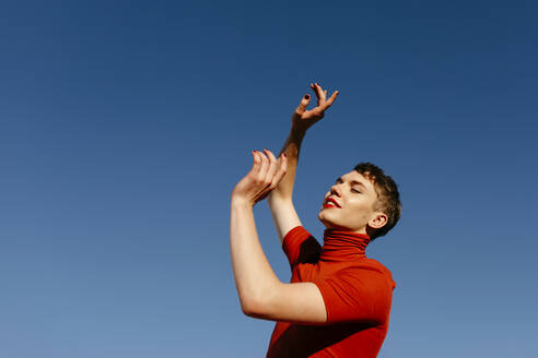 Gender fluid man dancing against clear sky on sunny day - TCEF01091