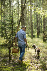 Mann geht mit seinem Hund im Wald spazieren - MAEF13027