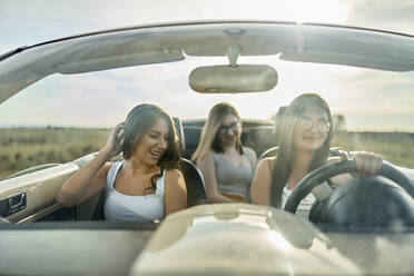 Friends having fun while traveling in convertible car for road trip - ZEDF03791