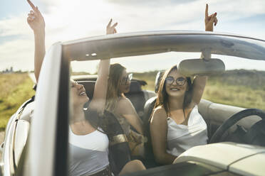 Young female friends having fun while dancing in convertible car - ZEDF03792