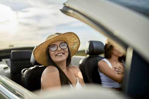 Junge lächelnde Frau, die mit einem Freund im Cabrio unterwegs ist - ZEDF03794
