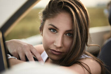 Beautiful young woman sitting in convertible car - ZEDF03810