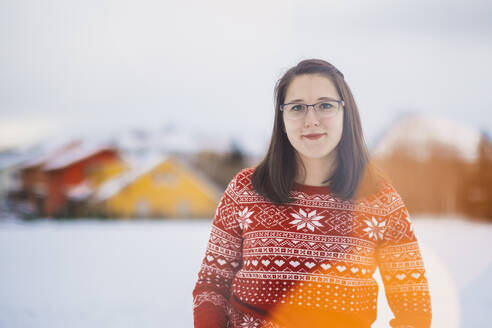 Lächelnde junge Frau steht auf schneebedecktem Land gegen den Himmel - JSCF00157