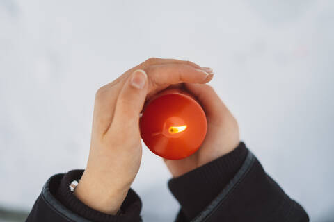 Close-up of young woman hands holding candle over snow covered land stock photo