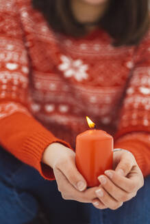 Close-up of young woman holding burning candle while sitting outdoors - JSCF00162