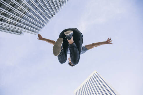 Young man performing parkour against sky in city - ABZF03331
