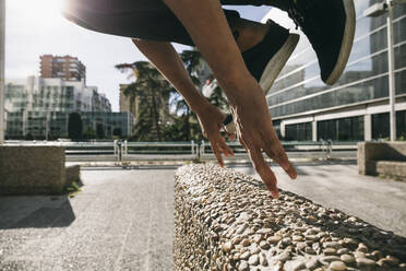 Beine eines jungen Mannes, der über eine Mauer springt und Parkour in der Stadt macht - ABZF03332