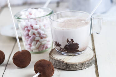 Nahaufnahme von heißer Schokolade mit Trüffel-Lutschern und Marshmallows auf dem Tisch zu Hause - SBDF04386